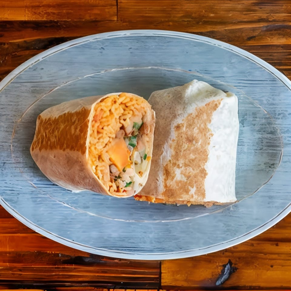Cut-open burrito filled with rice, beans, vegetables, and melted cheese on a blue plate atop a wooden table.
