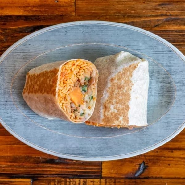 Two burritos, one cut open to reveal rice, beans, and vegetables, on a blue plate.